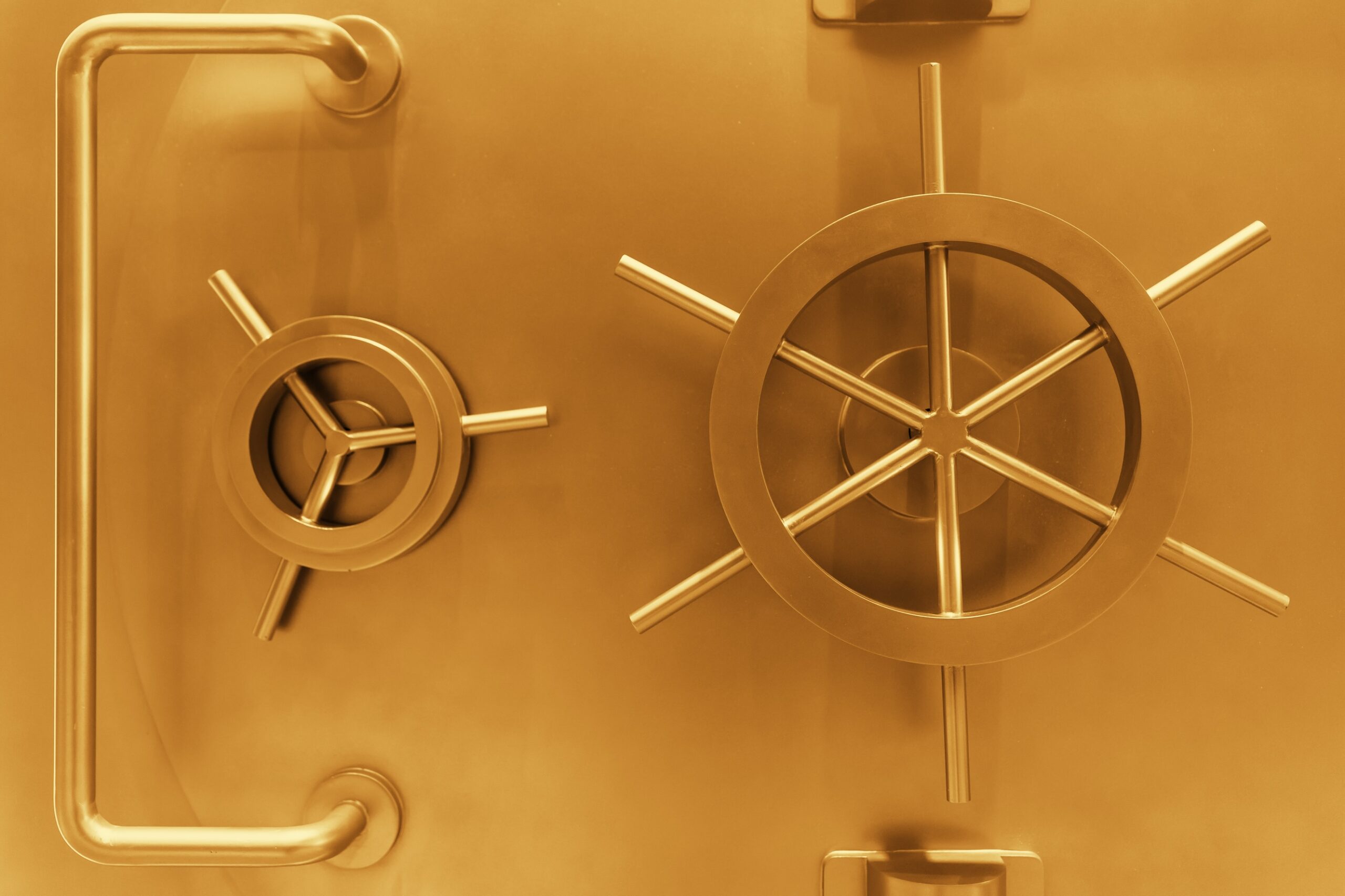 Close-up of a gold-toned bank vault door with a large wheel lock, a secondary lock, and a handle, symbolizing strong protection, encryption, and access control for AI data security.